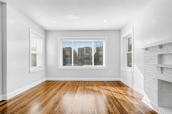 a view of an empty room with a window and wooden floor