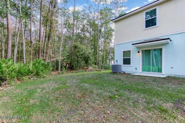 a view of a white house next to a yard with big trees