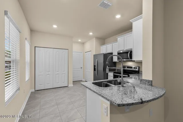 a kitchen with stainless steel appliances granite countertop a sink a refrigerator and a granite counter tops