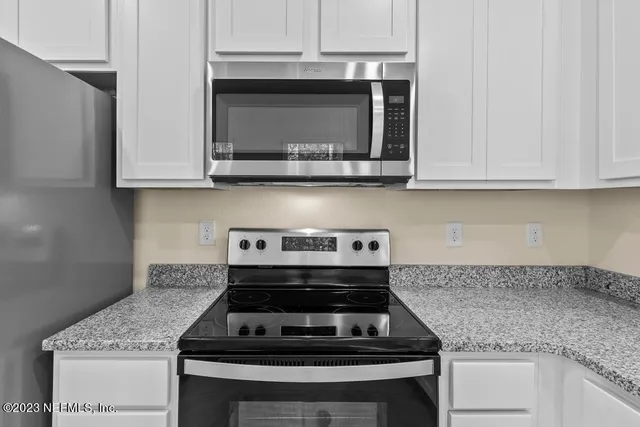a kitchen with granite countertop white cabinets and stainless steel appliances