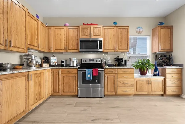 a room view with stainless steel appliances kitchen island granite countertop a refrigerator and a sink