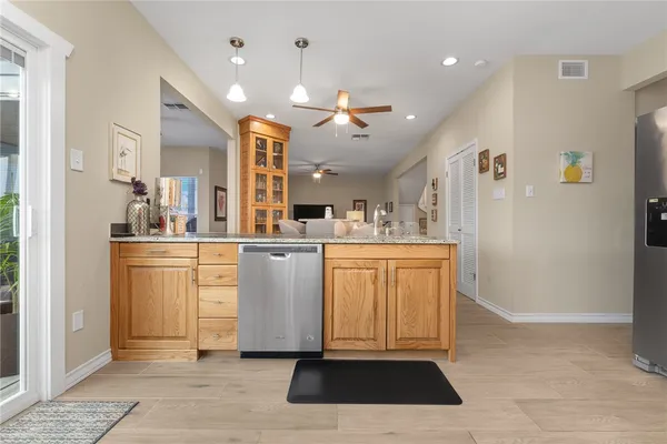 a kitchen with stainless steel appliances granite countertop a refrigerator stove top oven and sink with wooden floor