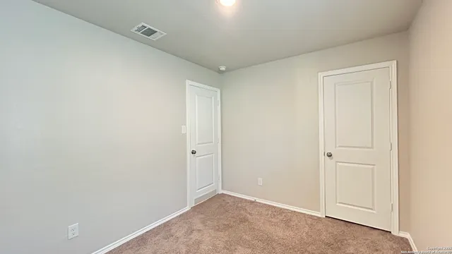 an empty room with a chandelier fan and windows