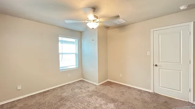 a view of an empty room and chandelier fan