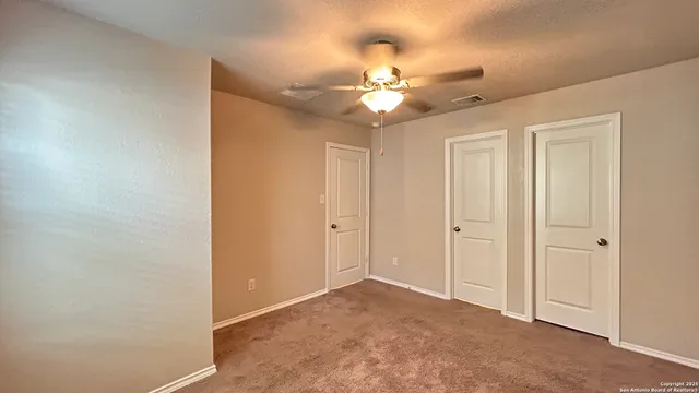 a view of an empty room and chandelier fan