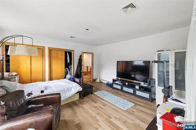 a bedroom with a bed and a flat tv screen on dresser