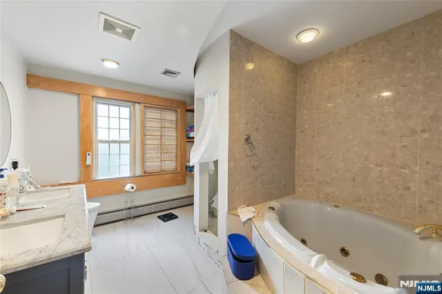 a bathroom with a tub a sink and a large mirror