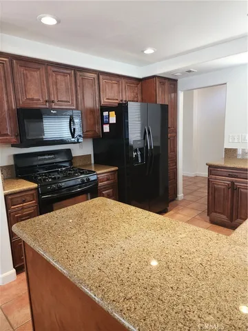 a kitchen with stainless steel appliances kitchen island granite countertop a refrigerator and a stove top oven