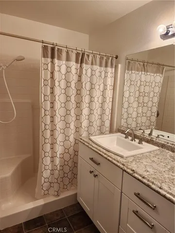 a bathroom with a granite countertop sink and a shower