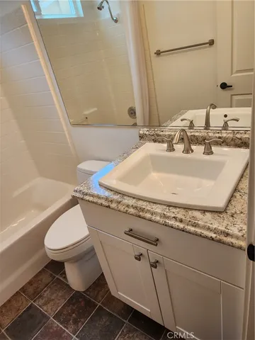 a bathroom with a granite countertop sink a toilet and a mirror