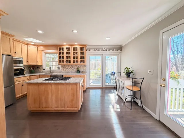 a kitchen with stainless steel appliances granite countertop wooden floors and white cabinets