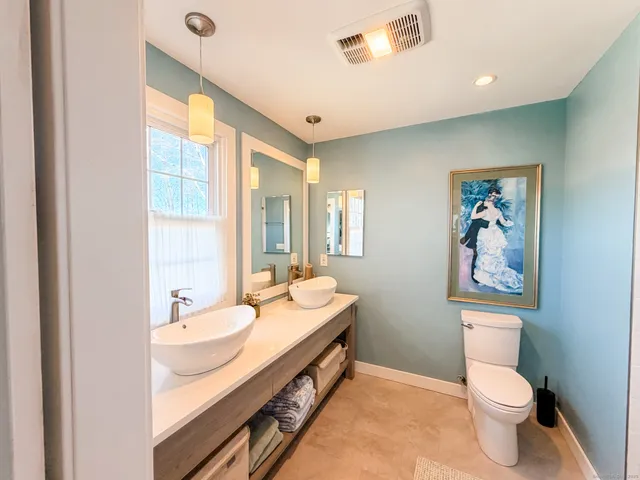 a bathroom with a double vanity sink toilet and a window