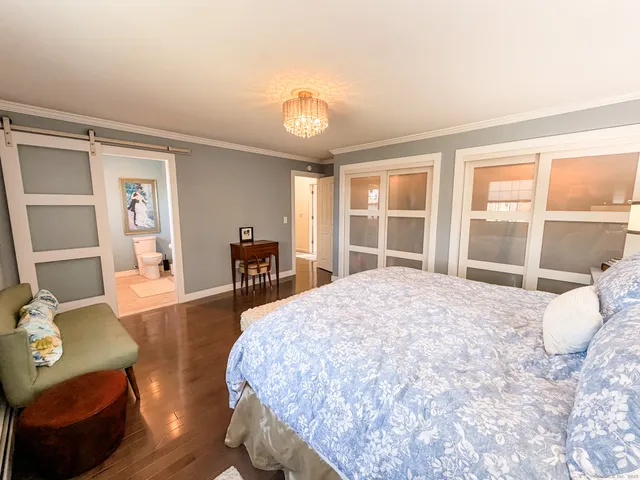 a large bedroom with wooden floor and furniture