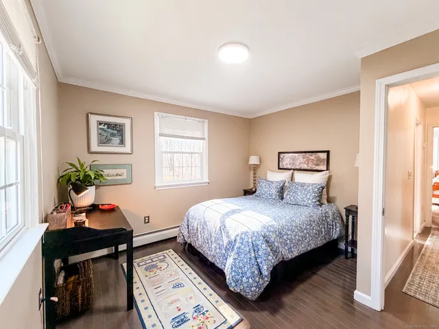 a bedroom with a bed table chair and a window