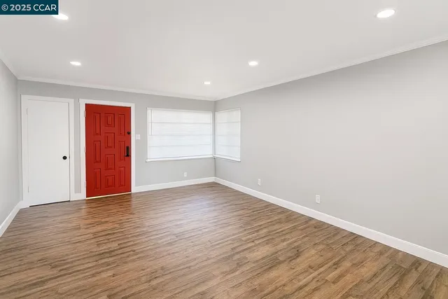a view of an empty room with wooden floor and windows