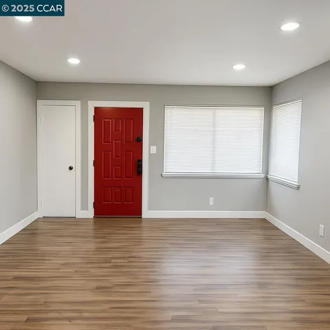 a view of an empty room with wooden floor and a window