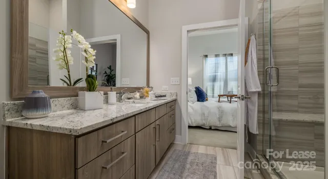 a bathroom with a granite countertop sink a mirror and shower
