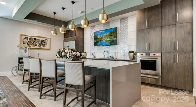 a kitchen with stainless steel appliances kitchen island granite countertop a table chairs and a refrigerator
