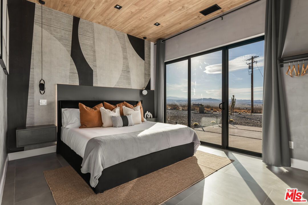 6765 Swanson Road Joshua Tree, CA 92252 - Photo 29 of 69 a bedroom with a large bed and a large window