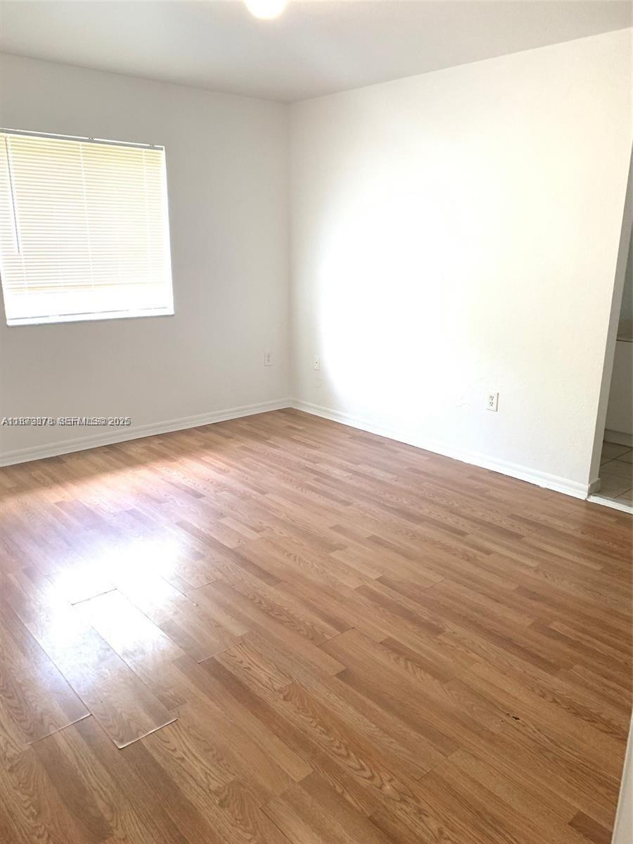 26232 Southwest 135th Place Homestead, FL 33032 - Photo 6 of 9 an empty room with wooden floor and windows