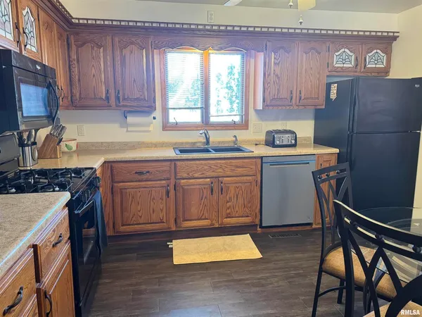 a kitchen with stainless steel appliances granite countertop a stove a sink dishwasher and a refrigerator with wooden cabinets