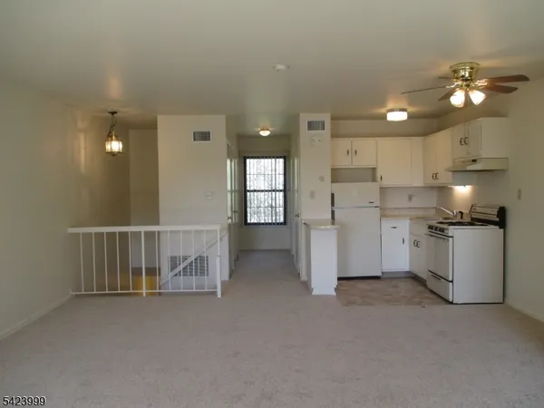 a view of a kitchen with a sink and dishwasher a refrigerator with white cabinets