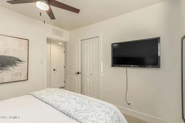 a bedroom with a flat screen tv and a chandelier fan