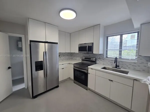 a kitchen with a refrigerator sink and cabinets