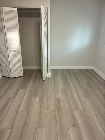 an empty room with wooden floor and closet