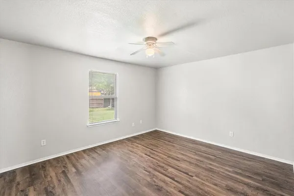 an empty room with wooden floor ceiling fan and windows