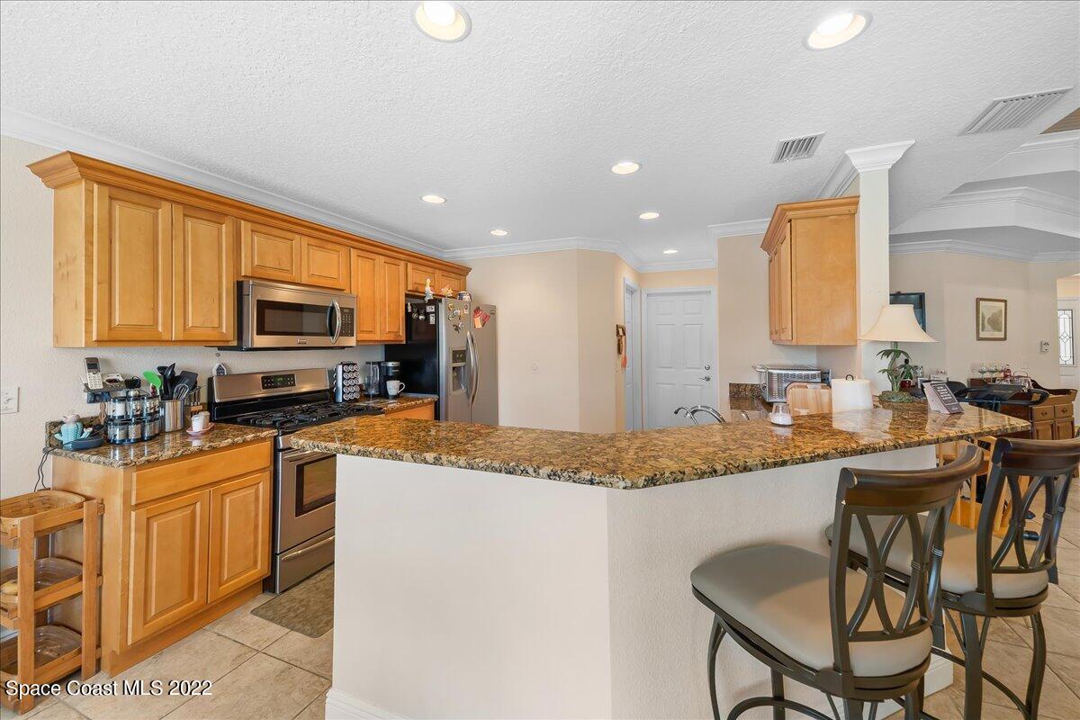 5265 Evinrude Road Melbourne, FL 32934 - Photo 12 of 42 a kitchen with stainless steel appliances granite countertop a stove top oven a sink a dining table and chairs