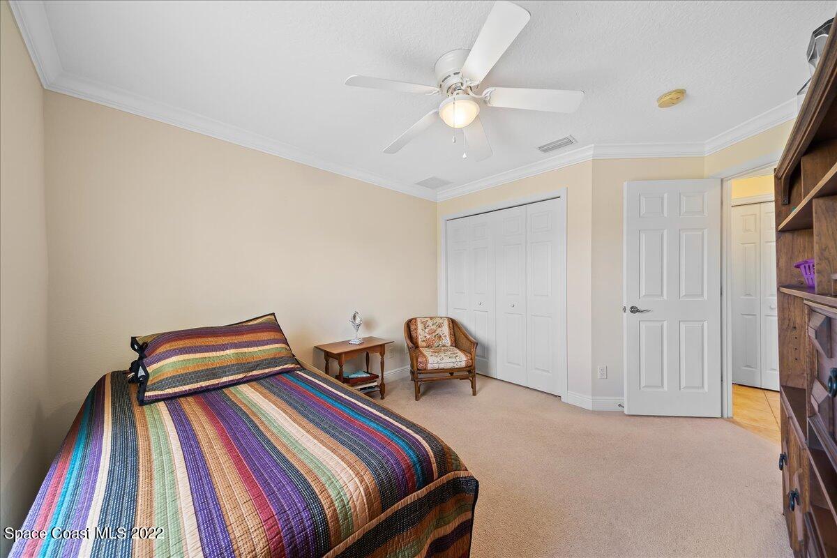 5265 Evinrude Road Melbourne, FL 32934 - Photo 26 of 42 a bedroom with a bed and a chandelier