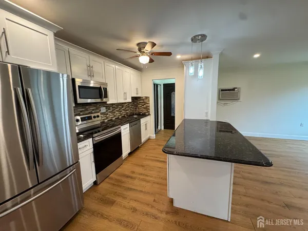 a kitchen with kitchen island granite countertop stainless steel appliances cabinets a sink and a refrigerator