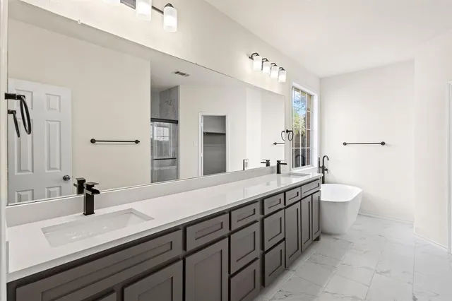 a spacious bathroom with a double vanity sink toilet and mirror