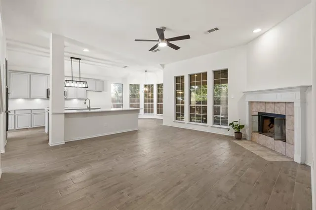 a view of a livingroom with a fireplace a ceiling fan and windows