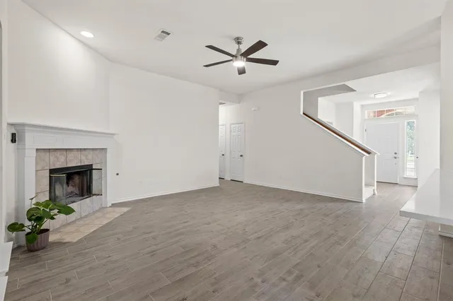 a view of a livingroom with a ceiling fan a fireplace and wooden floor
