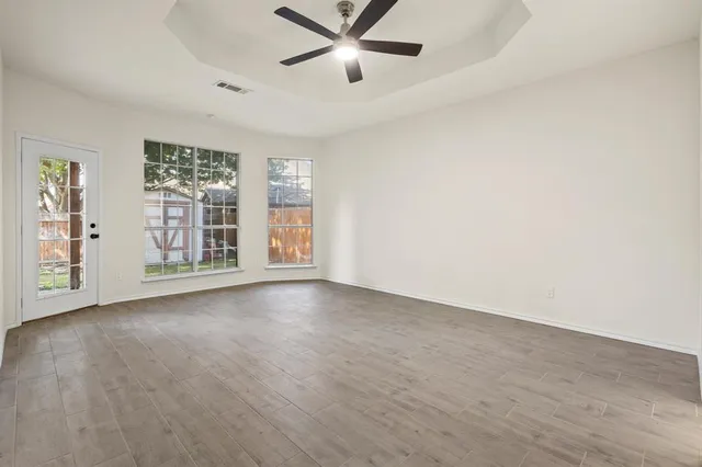 an empty room with windows and ceiling fan