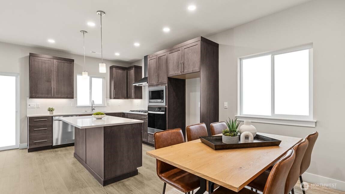 3125 194th Street Southeast Bothell, WA 98012 - Photo 4 of 25 a kitchen with a stove a sink a kitchen island with chairs and wooden floor