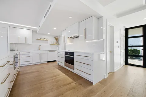 a kitchen with stainless steel appliances granite countertop white cabinets and wooden floors