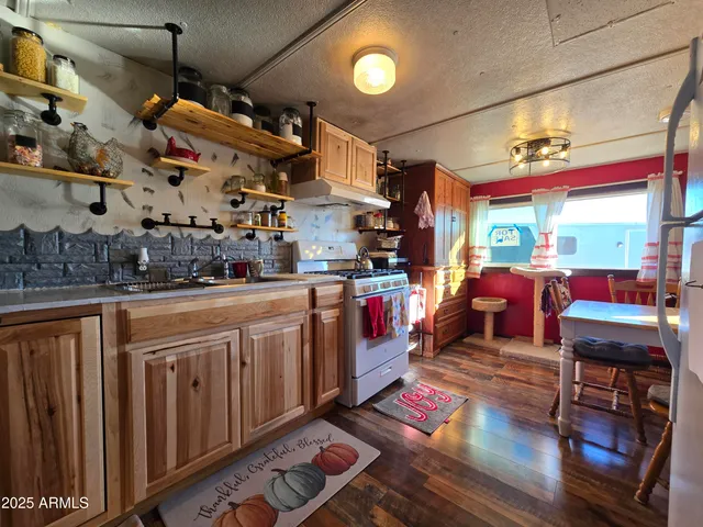 a open kitchen with stainless steel appliances granite countertop a stove a sink and dishwasher cabinets with wooden floor