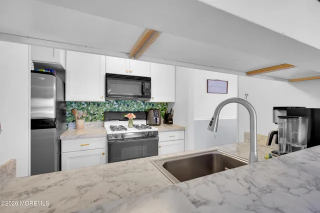 a kitchen with stainless steel appliances granite countertop a sink stove refrigerator and cabinets