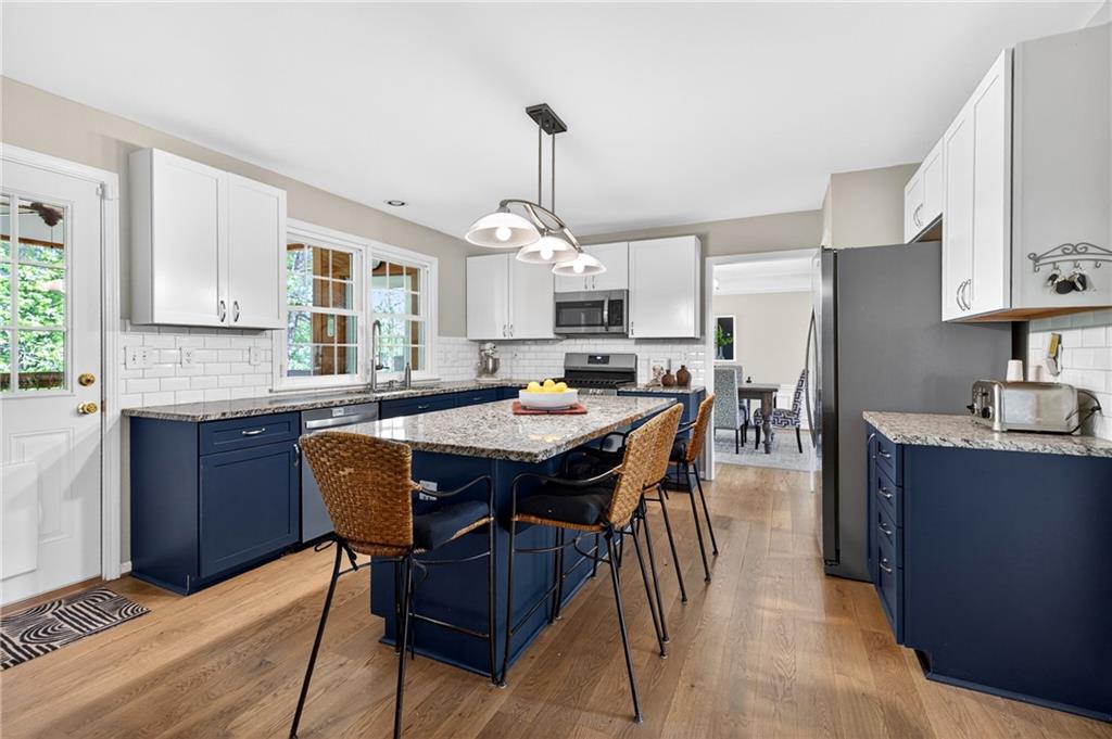 7830 Llangollen Way Cumming, GA 30041 - Photo 5 of 60 a kitchen with stainless steel appliances granite countertop a stove a sink dishwasher a dining table and chairs with wooden floor