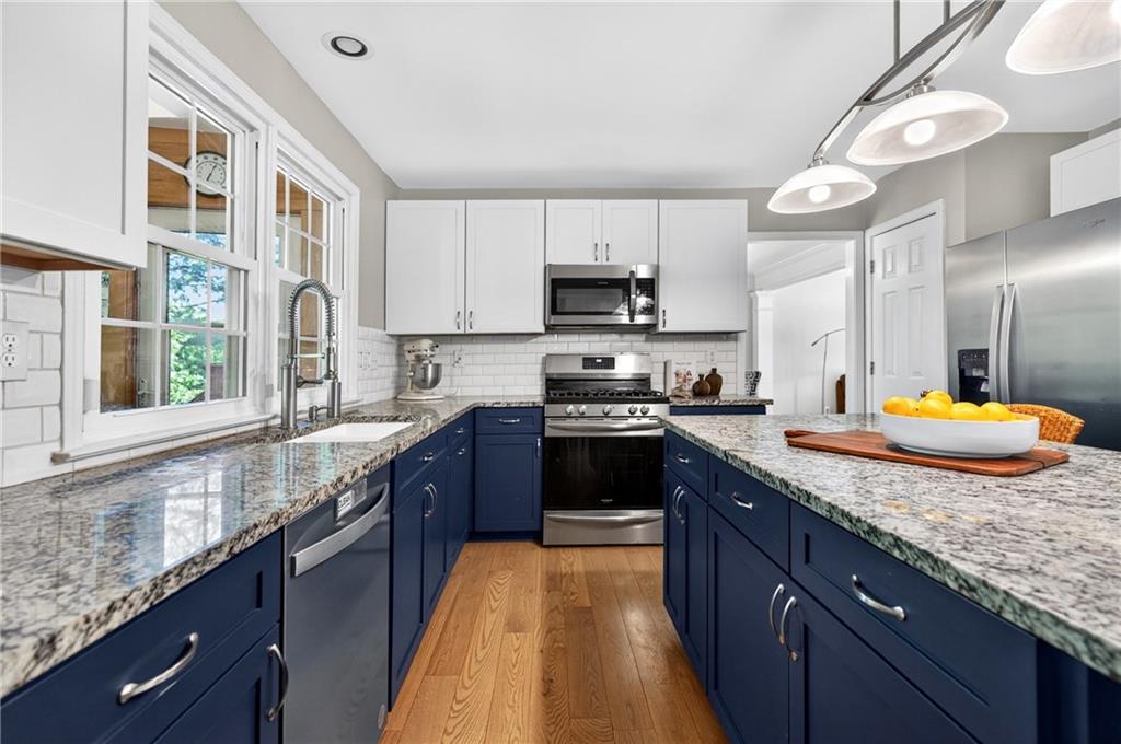 7830 Llangollen Way Cumming, GA 30041 - Photo 8 of 60 a kitchen with stainless steel appliances granite countertop a sink a stove and a wooden cabinets