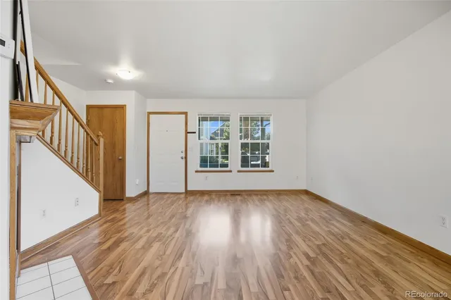 a view of an empty room with wooden floor fireplace and a window