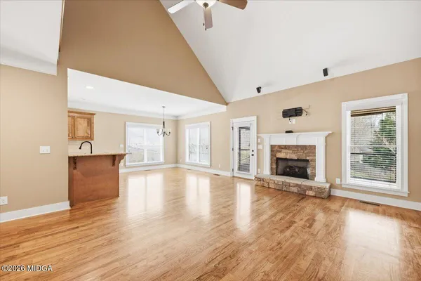 an empty room with wooden floor fireplace and windows