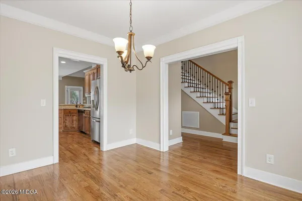 a view of a hallway with wooden floor and a chandelier