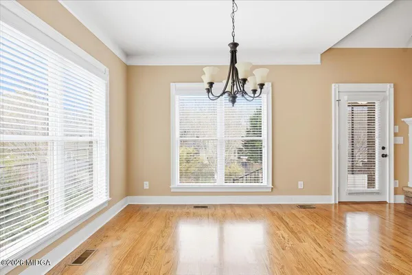 a view of an empty room with a window and wooden floor