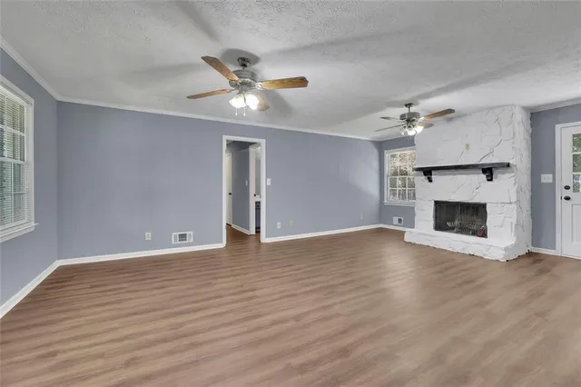a view of an empty room with wooden floor fireplace and a window