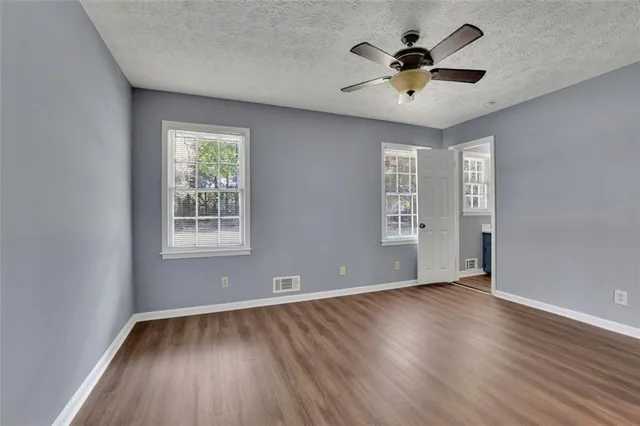 an empty room with wooden floor and windows