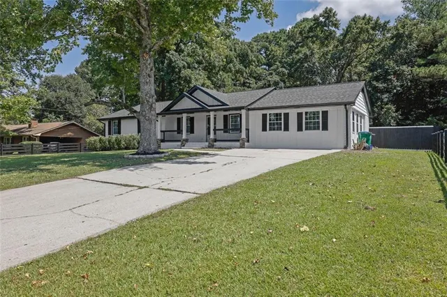a front view of a house with a garden and trees